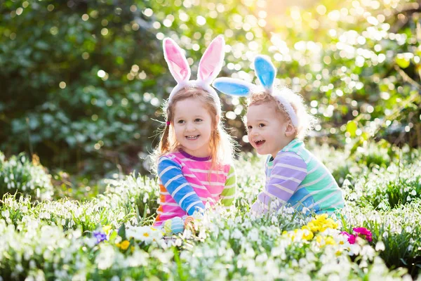 Kids on Easter egg hunt in blooming spring garden — Stock Photo, Image