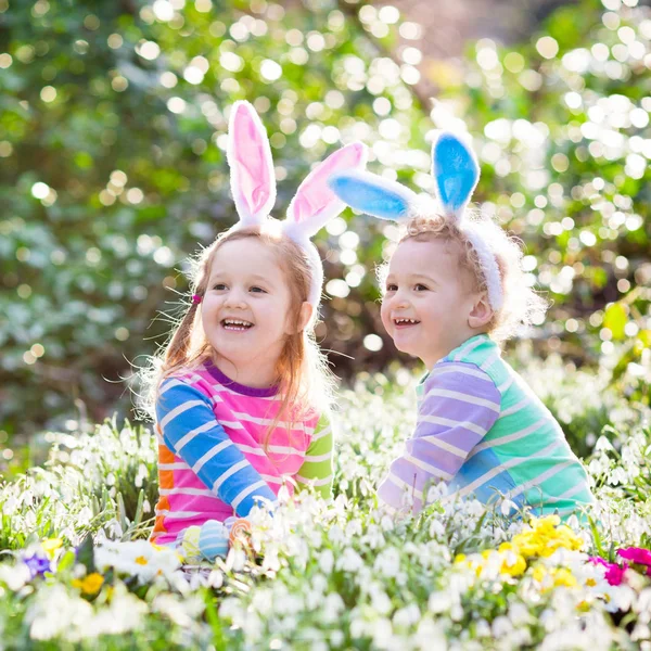 Kids on Easter egg hunt in blooming spring garden — Stock Photo, Image