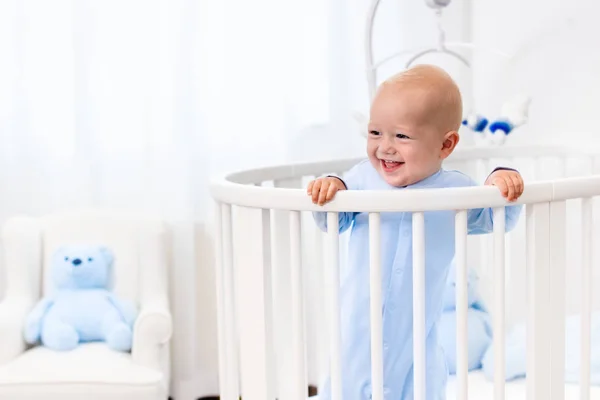 Niño de pie en la cama en el vivero blanco — Foto de Stock