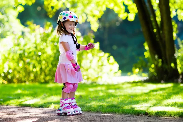 Liten flicka med roller skateskor i en park — Stockfoto