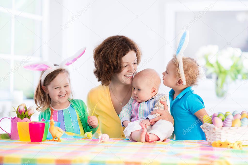 Mother with three children painting Easter eggs