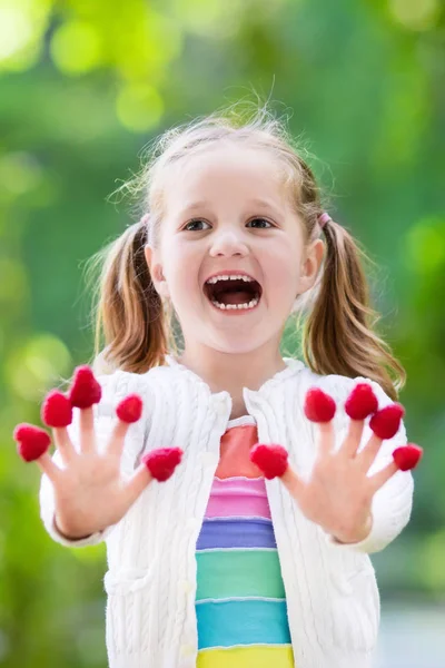 Child picking and eating raspberry in summer — Stock Photo, Image