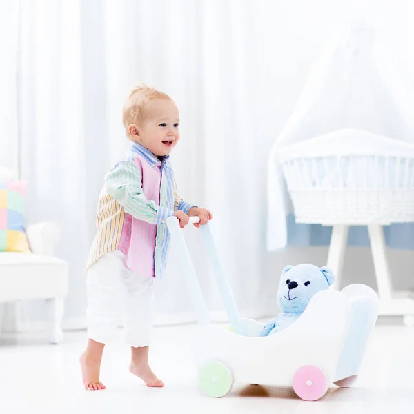 Bebê com caminhante push no quarto branco — Fotografia de Stock