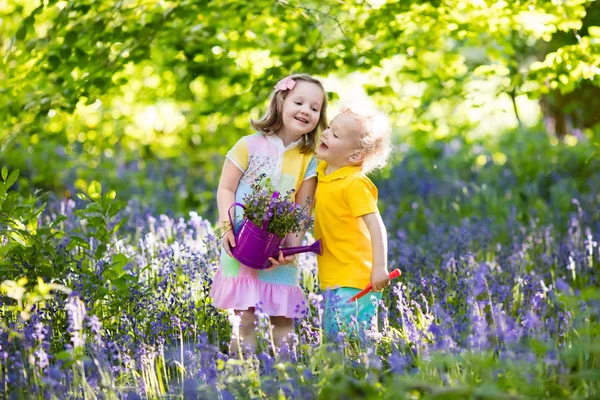 Kinderen spelen in de bloeiende tuin met bluebell bloemen — Stockfoto