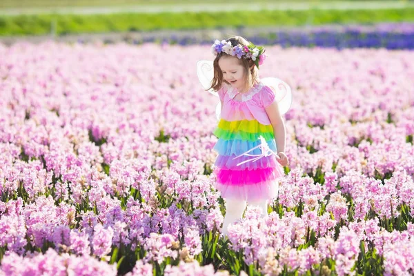 Little girl in fairy costume playing in flower field — Stock Photo, Image