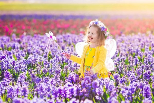 Klein meisje in fee kostuum op bloem gebied spelen — Stockfoto