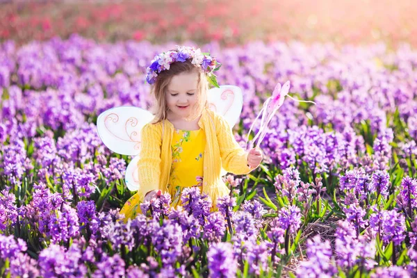Menina em fantasia de fada jogando no campo de flores — Fotografia de Stock