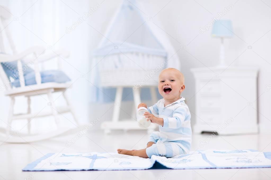 Baby boy drinking milk in sunny nursery