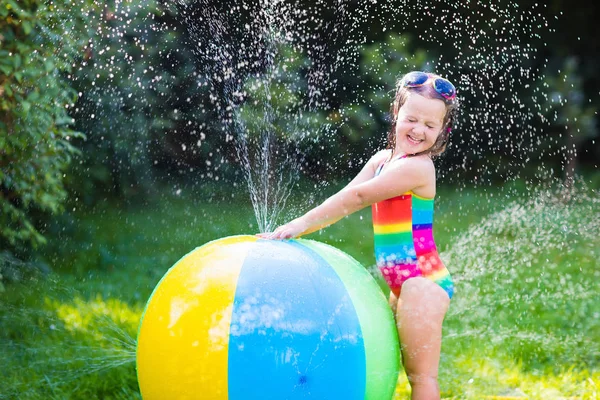 Oyuncak top Bahçe serpin ile küçük kız — Stok fotoğraf