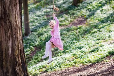 Ağaç ip salıncakta sallanan çocuk