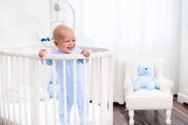 Beyaz kreş yatakta duran erkek bebek