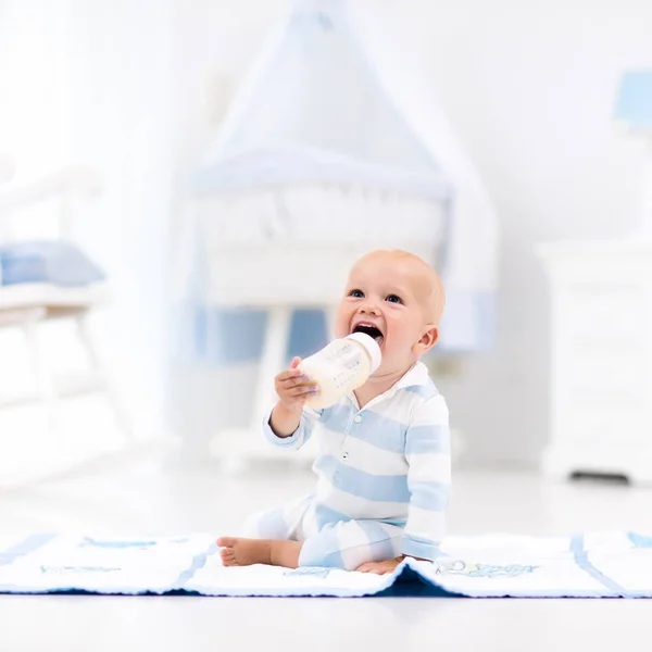Menino bebê bebendo leite em berçário ensolarado — Fotografia de Stock