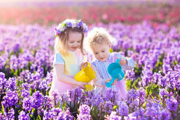 Kinderen planten en water bloemen in lentetuin — Stockfoto