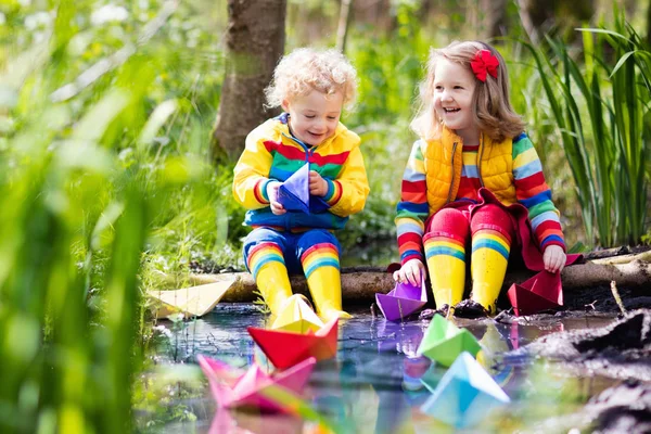 Crianças brincando com barcos de papel coloridos em um parque — Fotografia de Stock