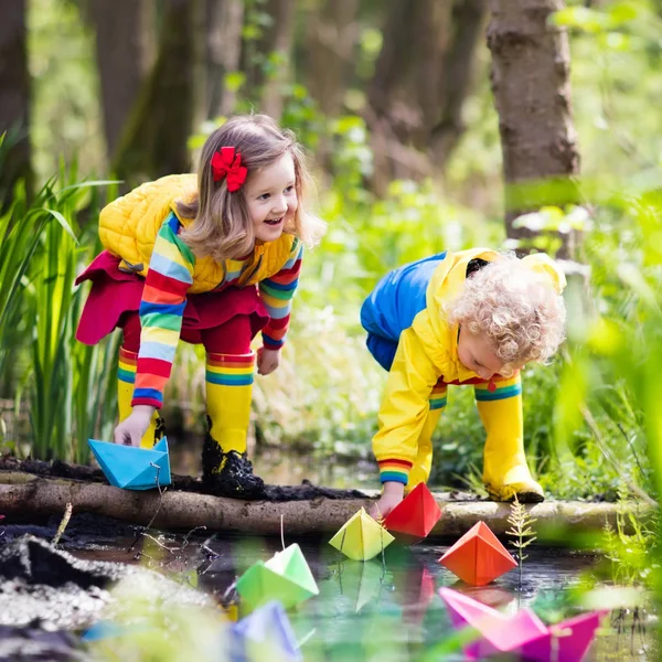 Bambini che giocano con barche di carta colorate in un parco — Foto Stock