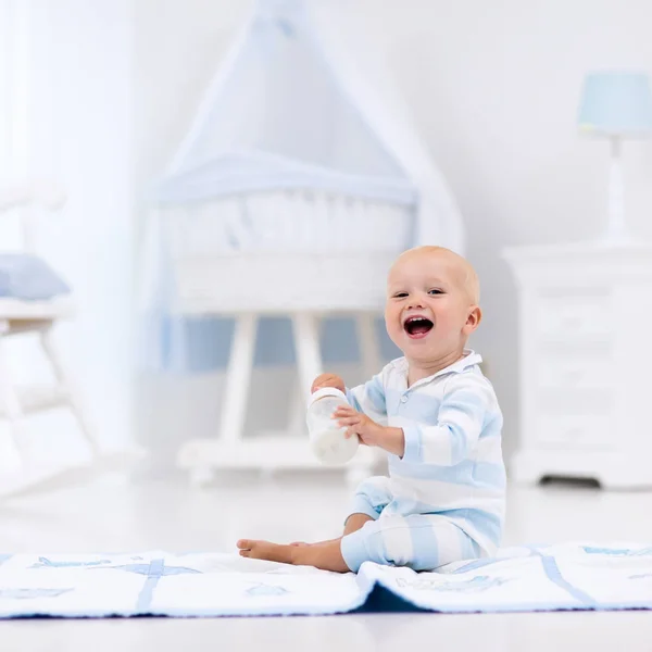 Babyjongen consumptiemelk in zonnige kinderkamer — Stockfoto