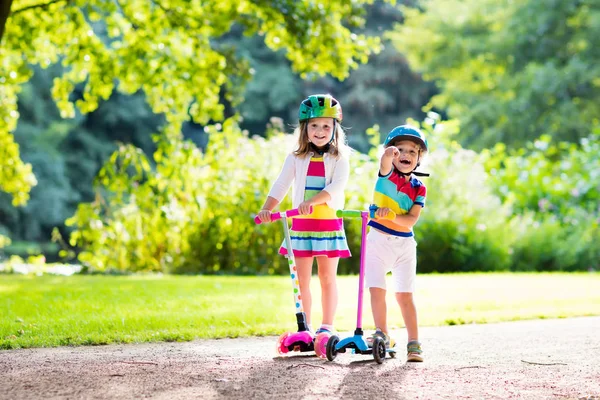 夏の公園でスクーターに乗る子供たち. — ストック写真