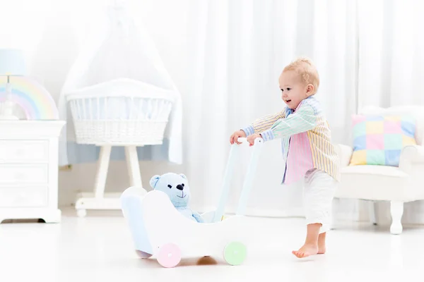 Baby with push walker in white bedroom