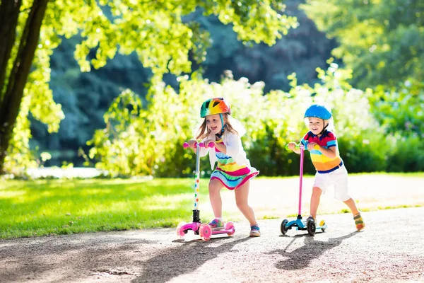 Barnen rider scooter i sommaren park. — Stockfoto