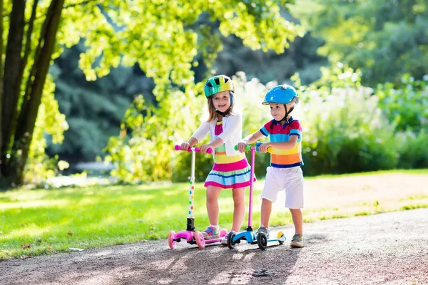 Barnen rider scooter i sommaren park. — Stockfoto