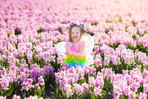 Little girl in fairy costume playing in flower field — Stock Photo, Image