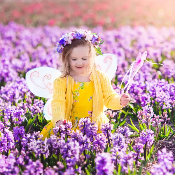 Niña en traje de hadas jugando en el campo de flores —  Fotos de Stock