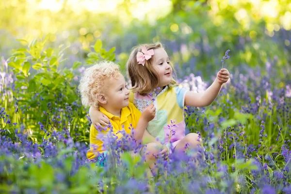 Niños jugando en el jardín floreciente con flores de Bluebell —  Fotos de Stock