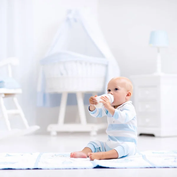 Baby boy drinking milk in sunny nursery — Stock Photo, Image