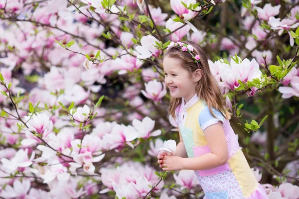 Barn med magnolia blomma. Liten flicka med blommor — Stockfoto