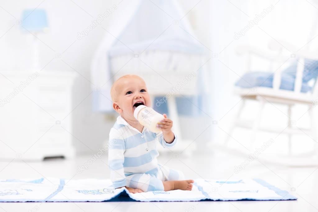 Baby boy drinking milk in sunny nursery