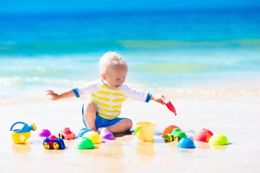 Tropik sahilde kum kazma oynayan bebek