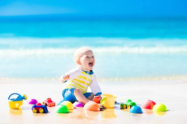 Baby playing on tropical beach digging in sand — Stock Photo, Image