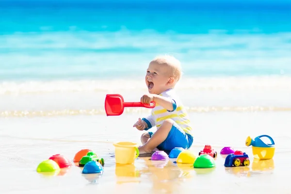 Baby playing on tropical beach digging in sand — Stock Photo, Image