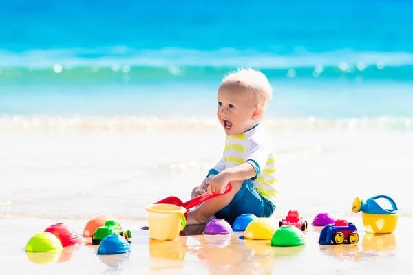 Baby playing on tropical beach digging in sand — Stock Photo, Image