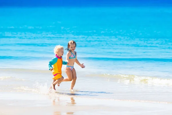 Børn løber og leger på tropisk strand - Stock-foto
