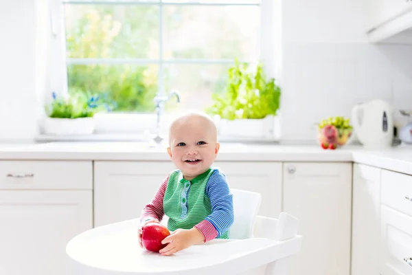 Niño comiendo manzana en la cocina blanca en casa —  Fotos de Stock