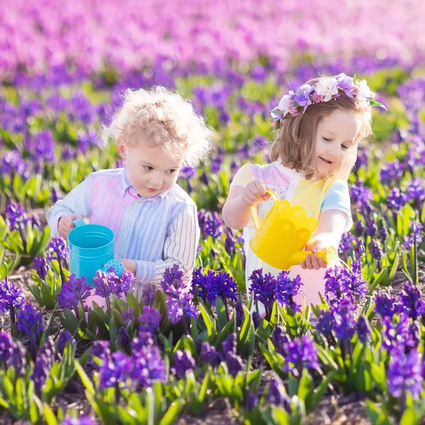 Kinder pflanzen und gießen Blumen im Frühlingsgarten — Stockfoto