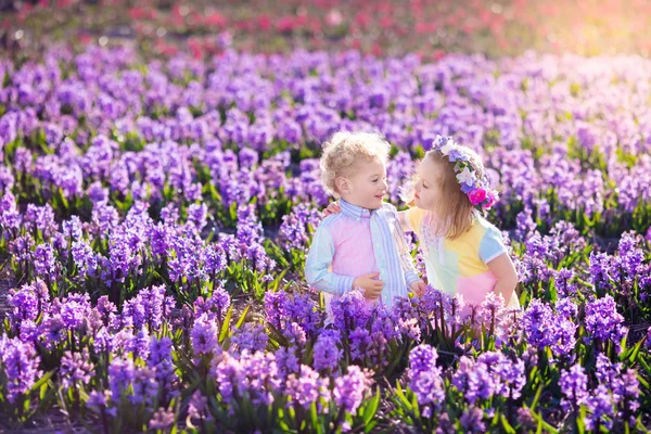 Niños jugando en el jardín floreciente con flores de jacinto —  Fotos de Stock