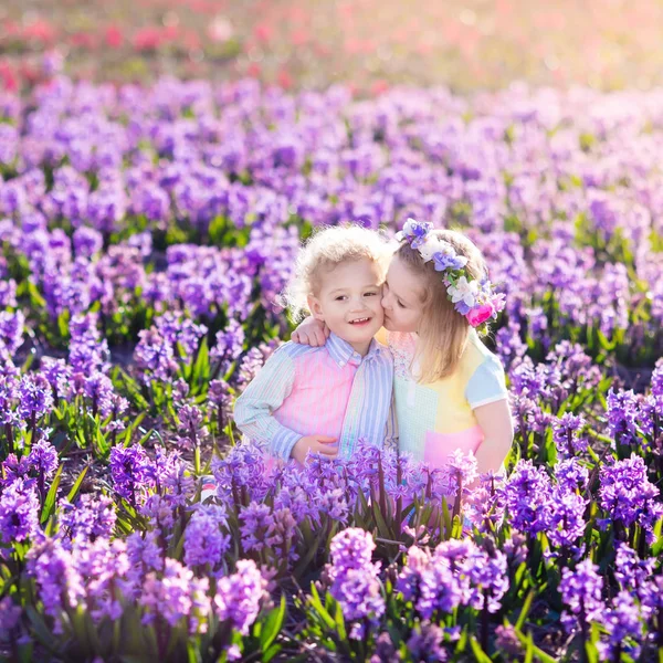 Niños jugando en el jardín floreciente con flores de jacinto —  Fotos de Stock