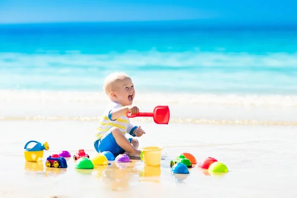 Bebé jugando en la playa tropical excavando en la arena — Foto de Stock