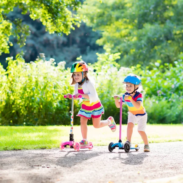 Kinderen rijden scooter in zomer park. — Stockfoto