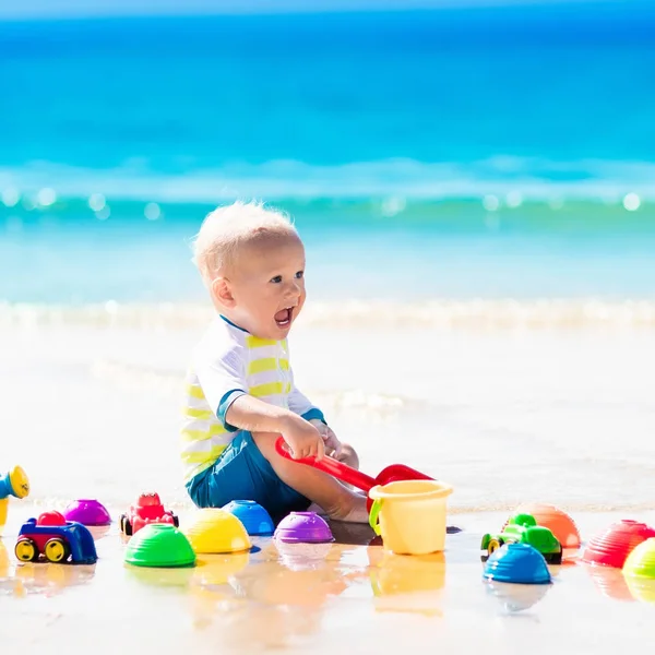 Bebé jugando en la playa tropical excavando en la arena —  Fotos de Stock
