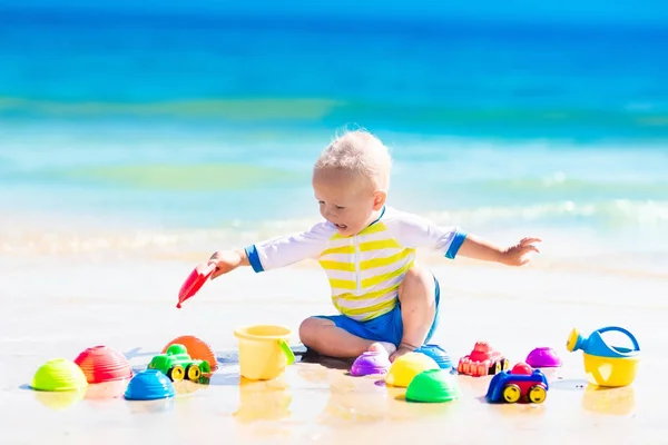 Baby playing on tropical beach digging in sand — Stock Photo, Image