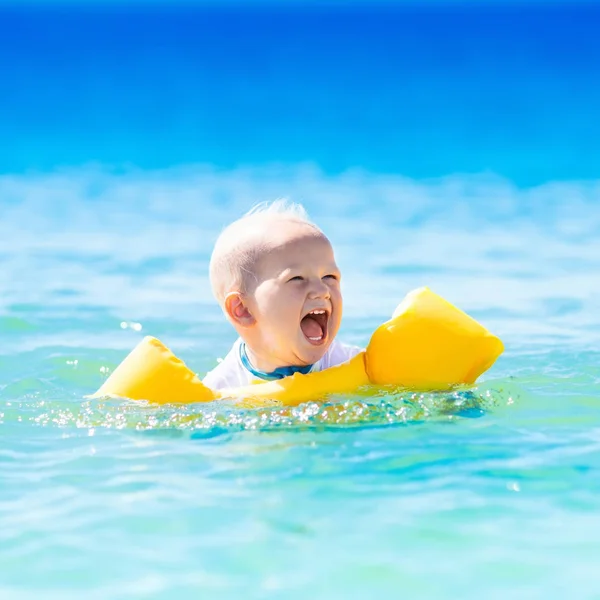 Baby pływanie w wodzie oceanu na tropikalnej plaży — Zdjęcie stockowe