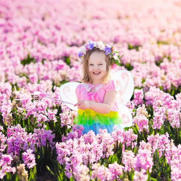 Klein meisje in fee kostuum op bloem gebied spelen — Stockfoto