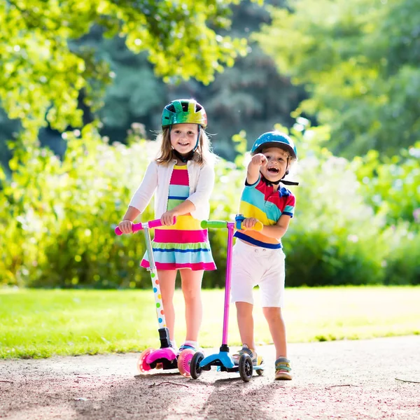 Crianças montando scooter no parque de verão . — Fotografia de Stock