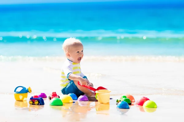 Bebé jugando en la playa tropical excavando en la arena — Foto de Stock