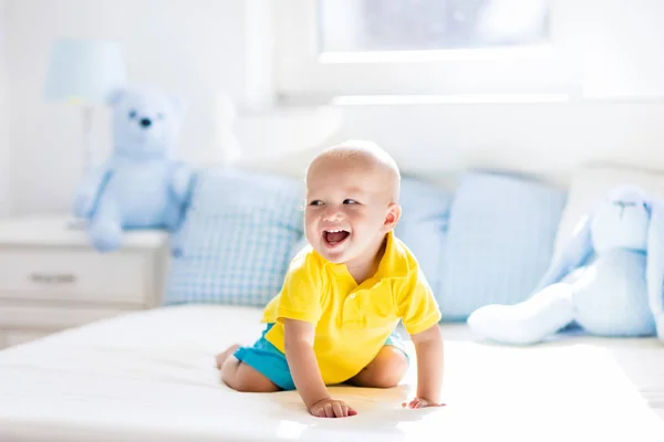 Baby pojke spelar på säng i soliga plantskola — Stockfoto