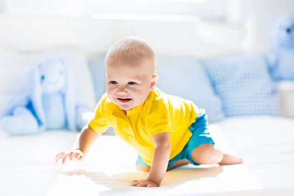 Baby boy playing on bed in sunny nursery