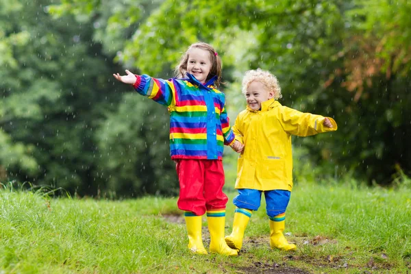 Barn leker i regn og sølepytt om høsten – stockfoto